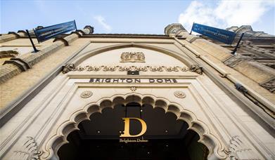 The exterior main entrance of Brighton Dome, the shot is taken looking up toward the Dome sign above an intricate doorway. 