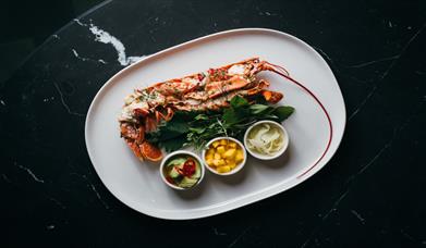 A plate of lobster with fresh mango salsa on a bed of greens. 