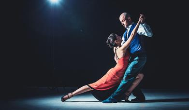 A woman in a red dress and her dance partner holding her