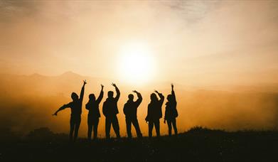 Silhouette of six people posing against a sunset