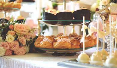 Cupcakes on stand with pink roses and small cakes beside them