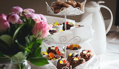 A white cake stand with roses beside it