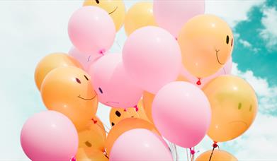 Yellow and pink balloons against a blue sky