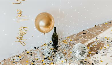Golden confetti and disco balls with champagne bottle on the floor