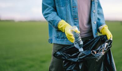 Yellow gloves placing a bottle in a bag