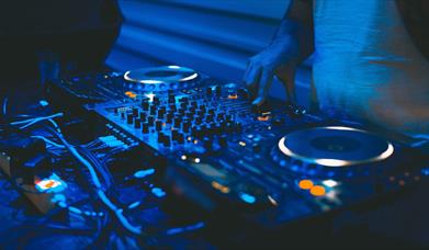 DJ and mixing decks in a blue light