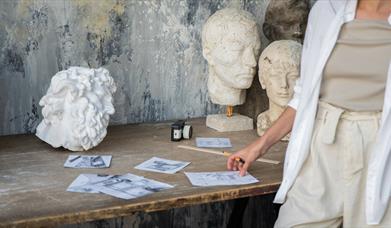 A selection of sketches and white sculptures on a table