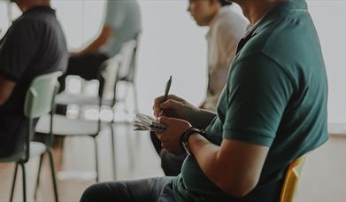 Person sitting in a chair taking notes on paper