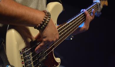 Person playing a white electric guitar