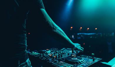 DJ working mixing decks in a green light