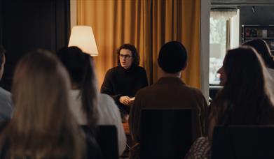 Long haired individual talking to a crowd