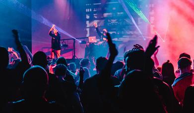 Performers beside blue and pink lights