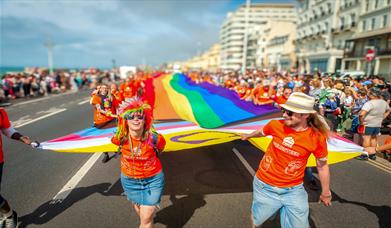 Image courtesy of Jim Carey. Pride revelers carrying a large Pride flag through the streets of Brighton to mark the start of the parade.