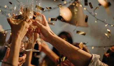 Image shows guests celebrating at a Private Christmas party at DoubleTree by Hilton Brighton Metropole. Champagne flutes are raised in the air whilst