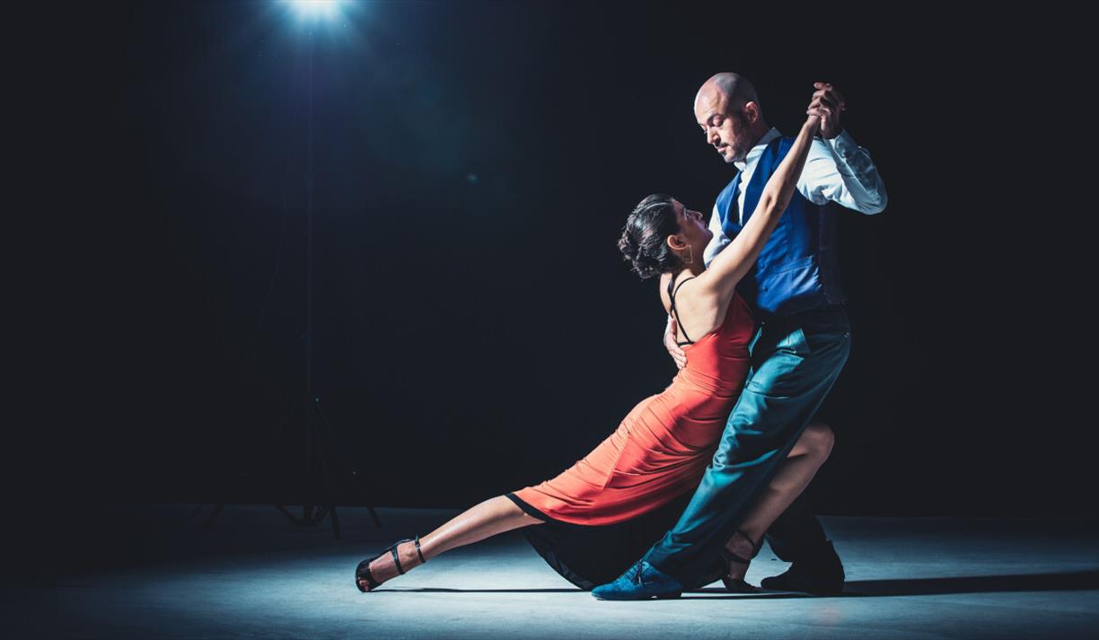 A woman in a red dress and her dance partner holding her