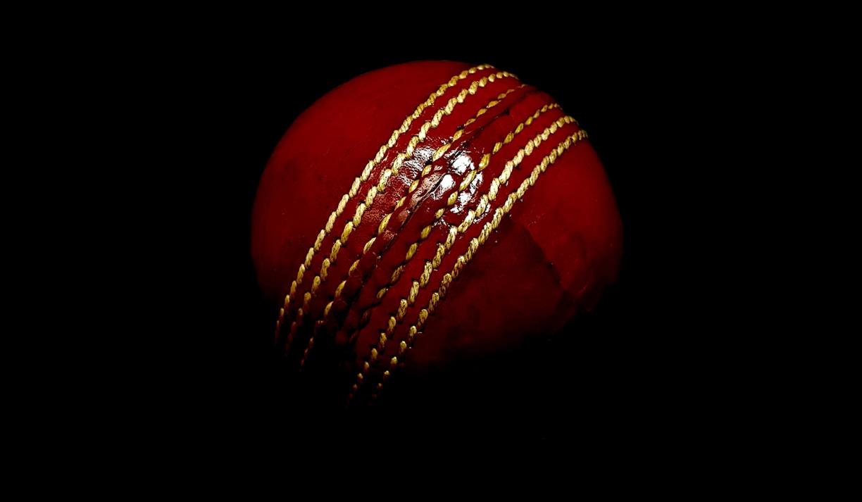 Red cricket ball on dark background