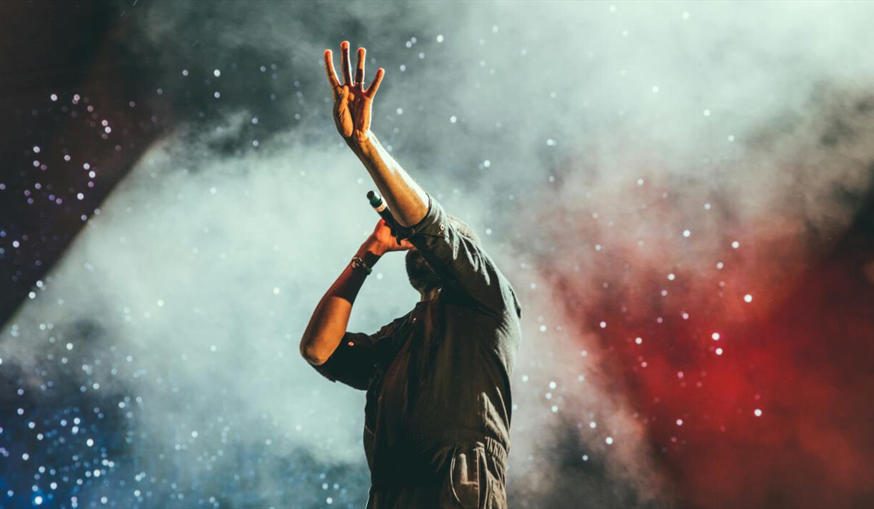 Person with hand raised and holding a microphone