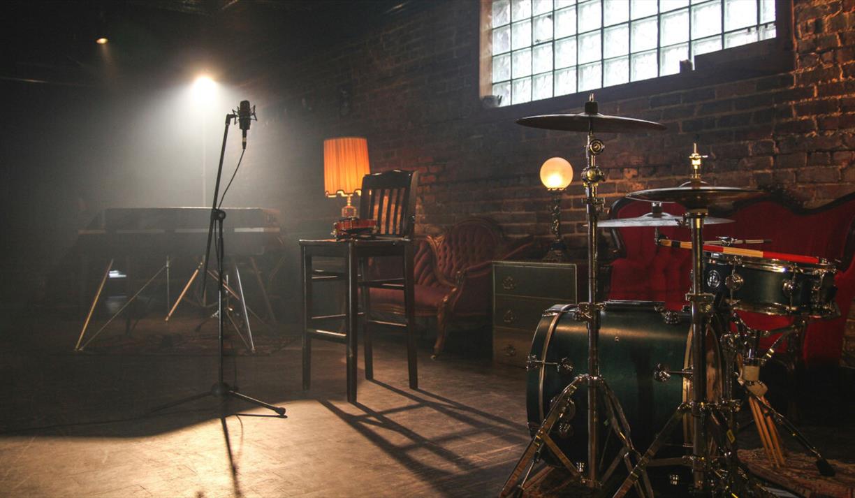 Microphone and drum kit in warmly lit room