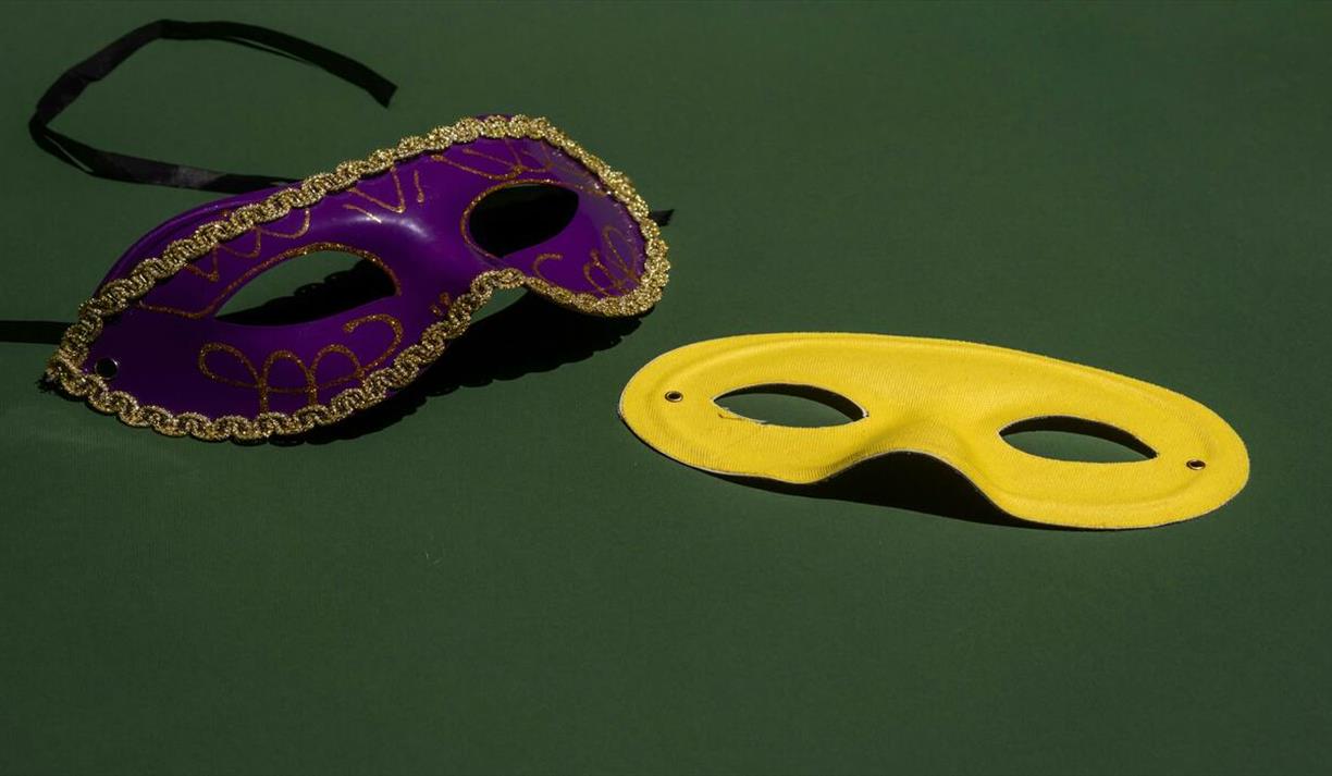 Purple and yellow masquerade masks on green background
