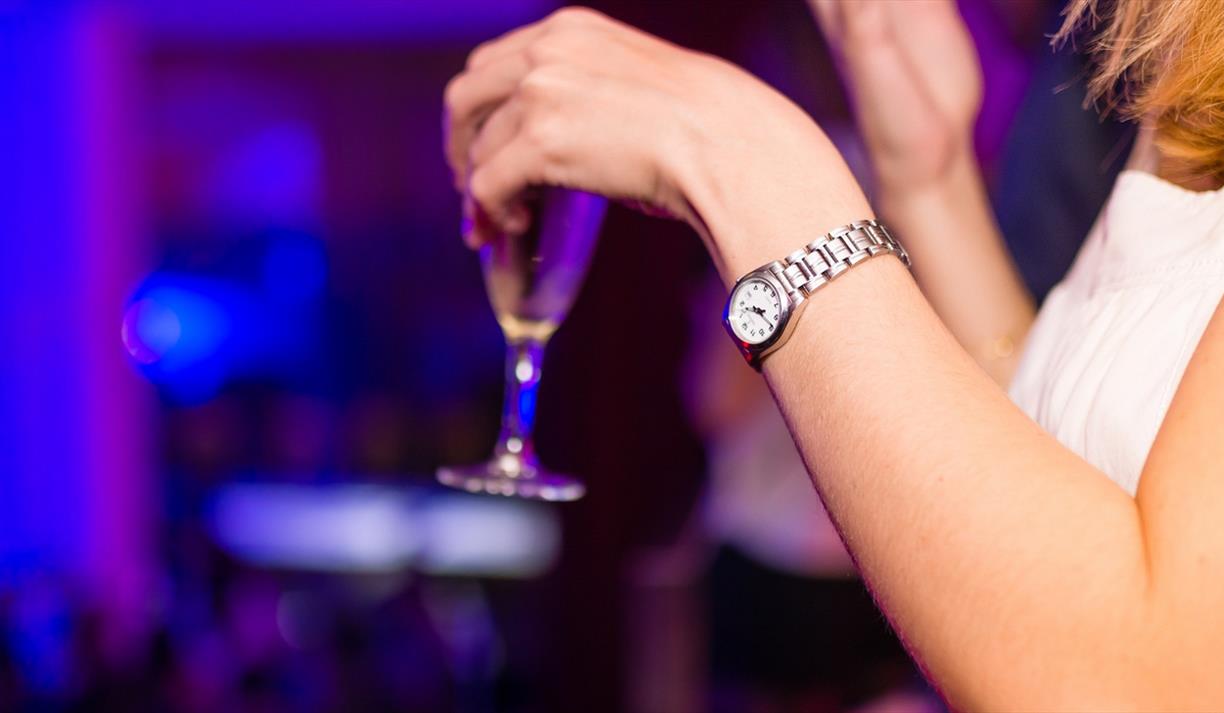 Hand with silver watch holding a glass