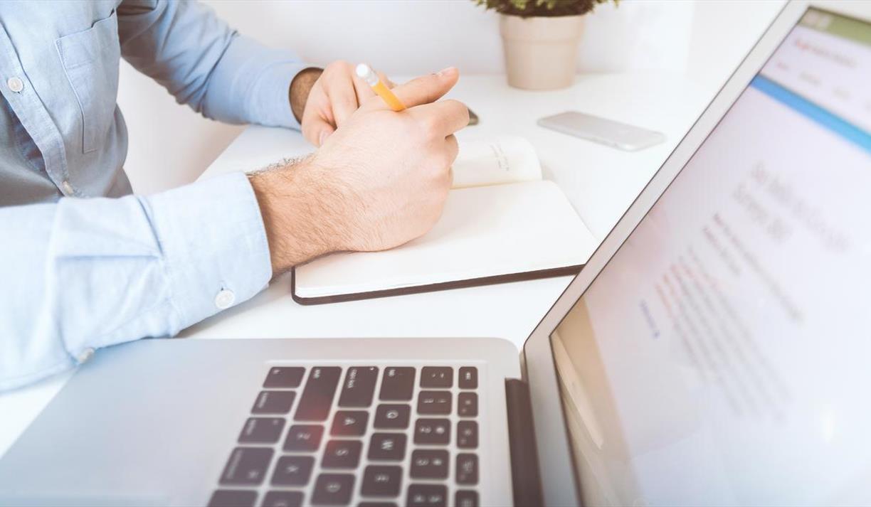 White laptop and man writing in notebook