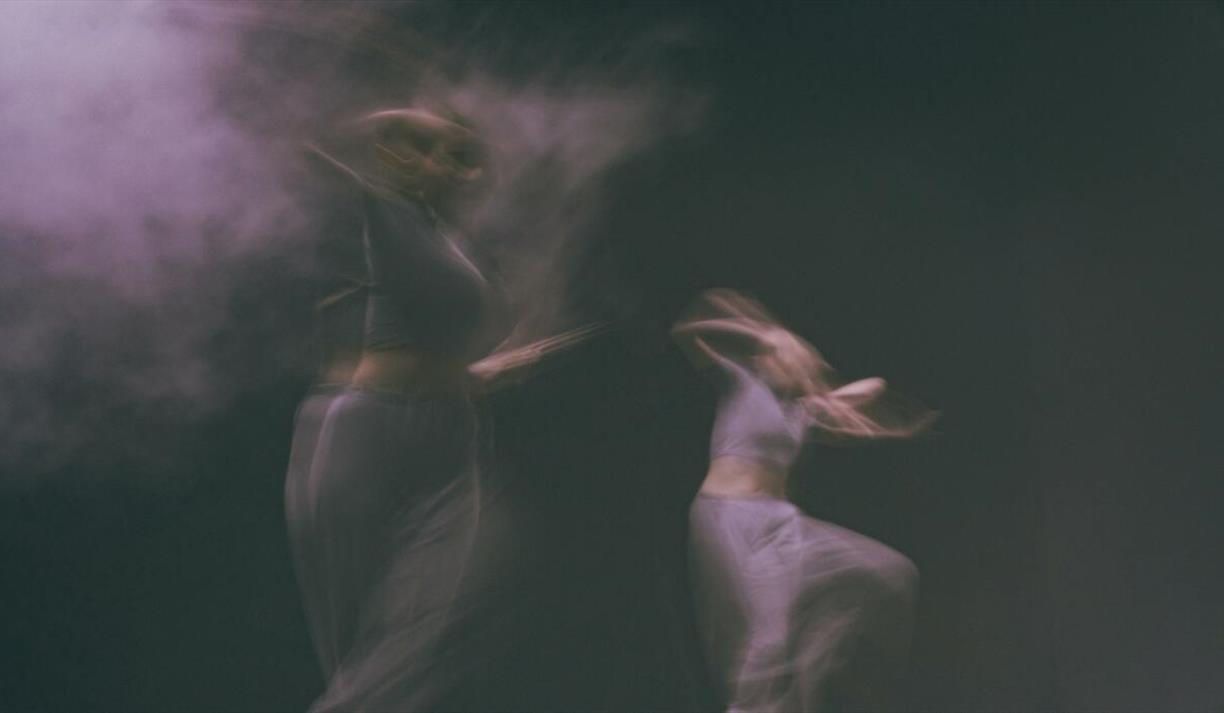 Dark studio with two dancers moving with motion blur effect