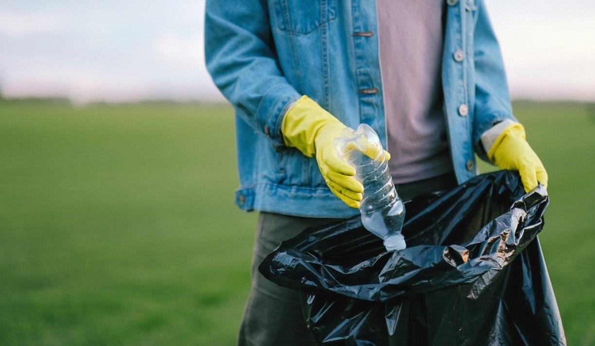Yellow gloves placing a bottle in a bag