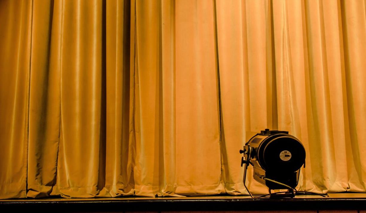 Dark yellow velvet stage curtain with spotlight in foreground