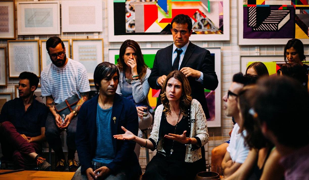 Group of people having a discussion with art on walls behind them