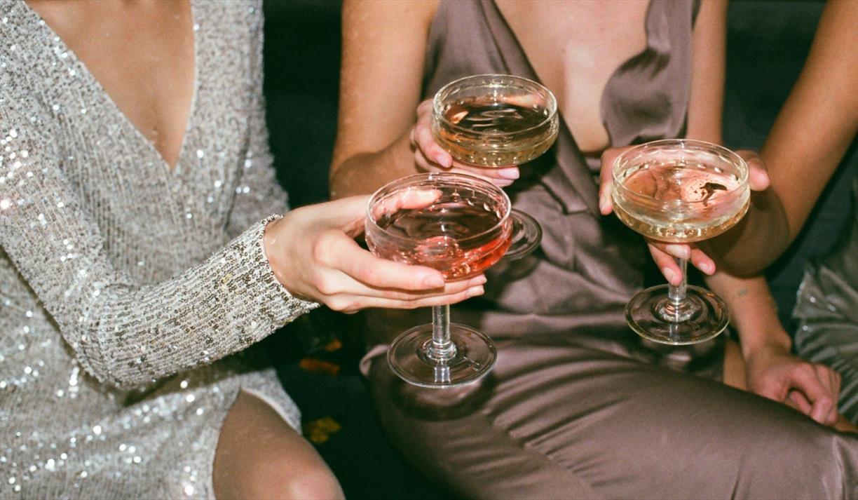 Three women in glittering dresses with shallow glasses