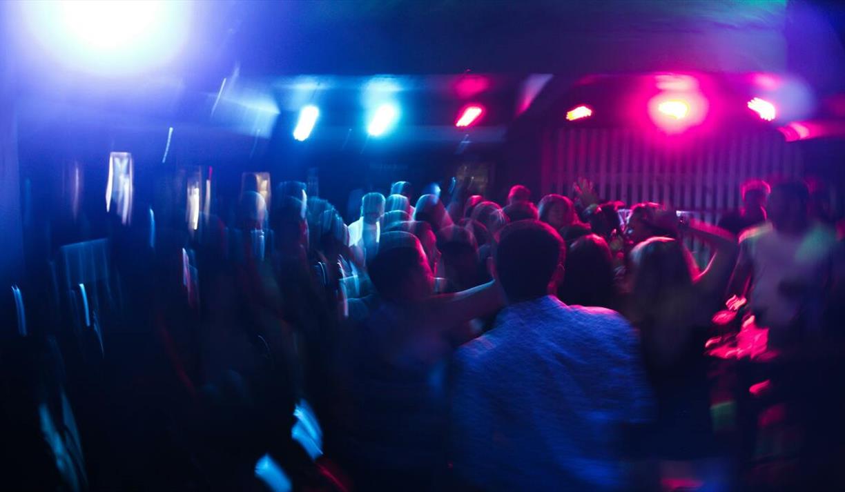 Vibrant nightclub scene with blurred dancing crowd and colorful lights