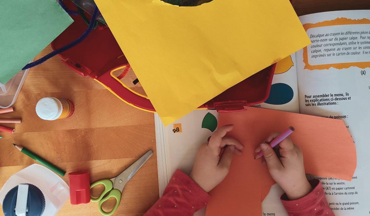 A child surrounded by bright cardboard at a craft table