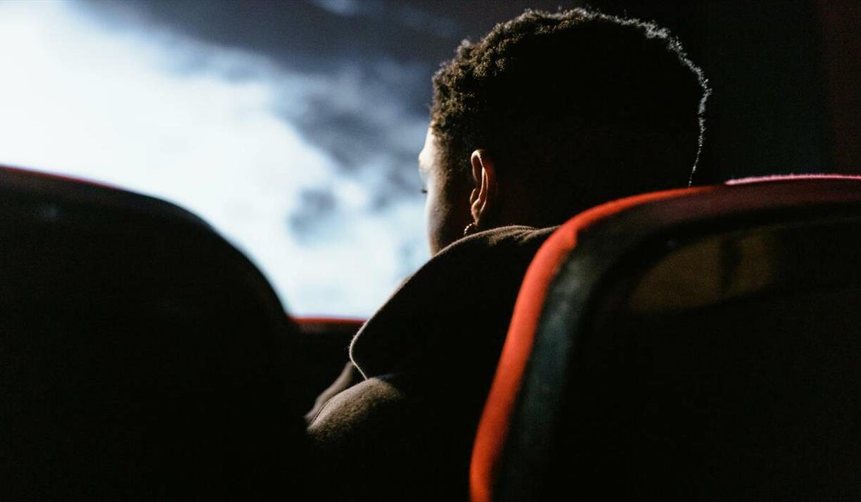 Side-view of person sitting in a cinema watching a movie on a large screen