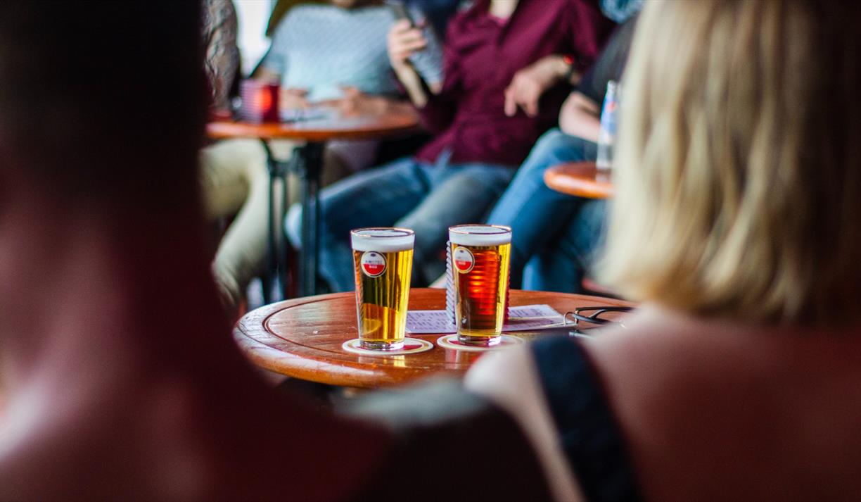 Two pints of beer on a table in a group of people