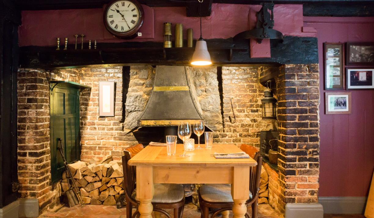 Table in front of a large roaring fireplace.