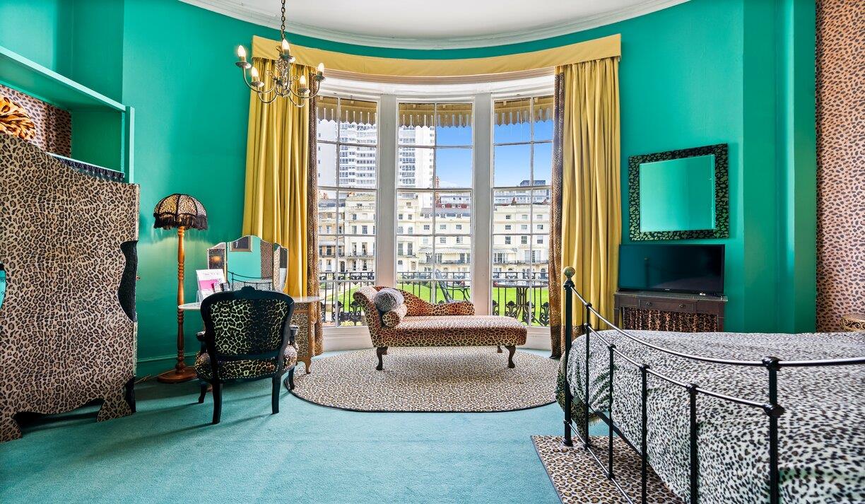Betties Boudoir room at Hotel Pelirocco showing a green room with a leopard print bedcover and wall hangings.