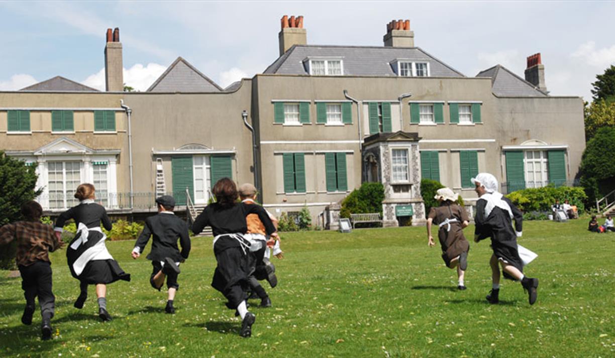 Children in historic dress running on lawn