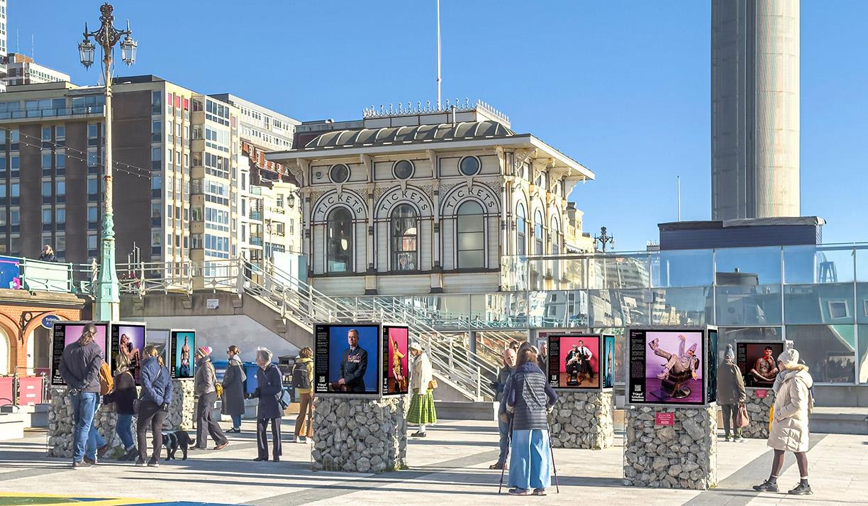 People viewing photographs at the outdoor Seafront Gallery by Brighton i360.