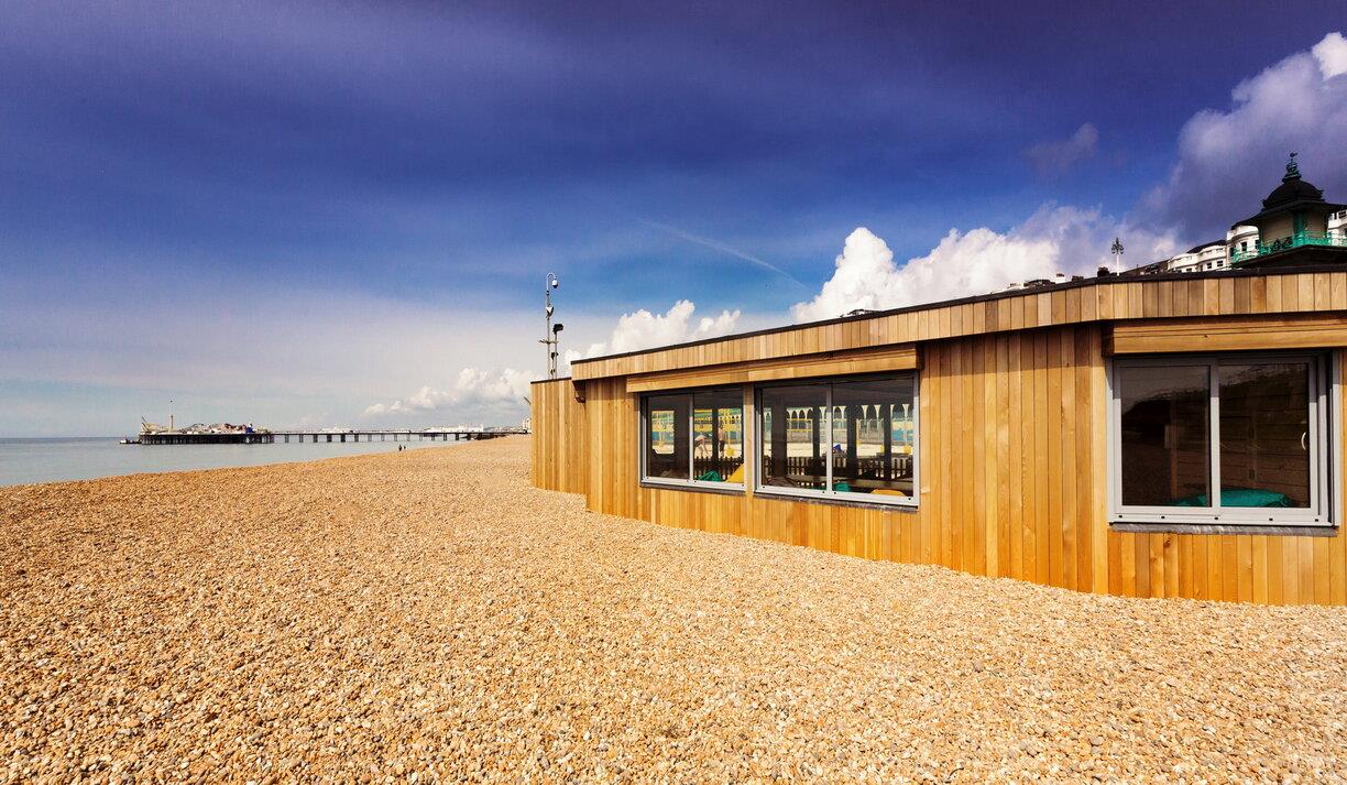 Outside shot of the Yellowave Beach House, a wooden structure with sand outside.