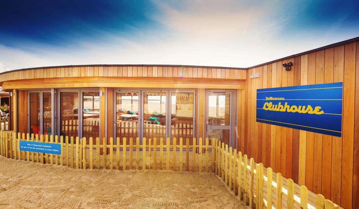 Outside shot of the Yellowave Beach House, a wooden structure with sand outside.
