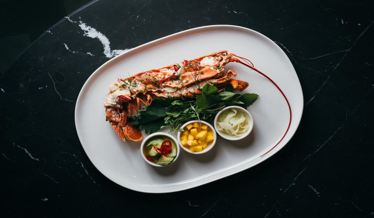 A plate of lobster with fresh mango salsa on a bed of greens.