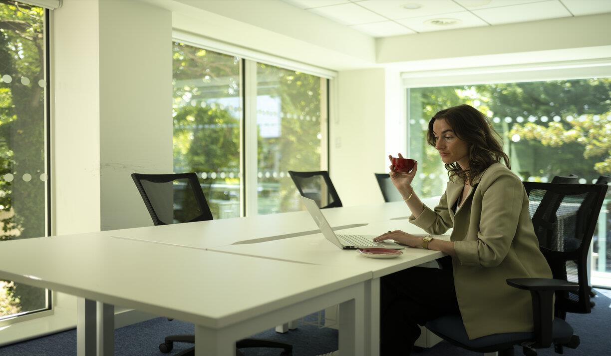 The workspace at BNJC workspace, a person sits at a table in a bright office space working on some documents.