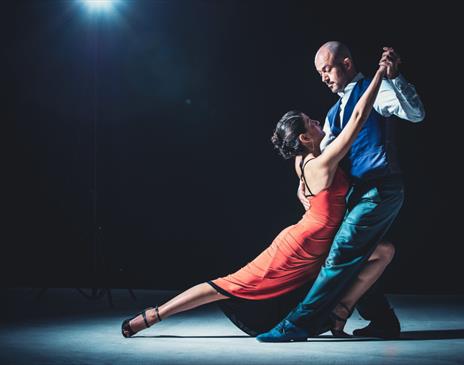 A woman in a red dress and her dance partner holding her