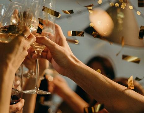 Golden confetti showering on party with wine glasses