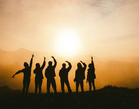 Silhouette of six people posing against a sunset