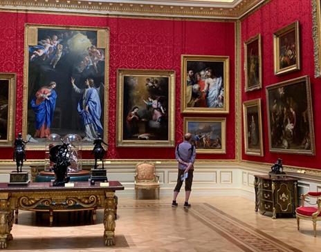 Man looking at painting in an opulent room