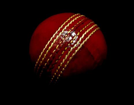 Red cricket ball on dark background