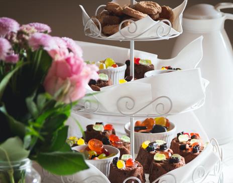 A white cake stand with roses beside it