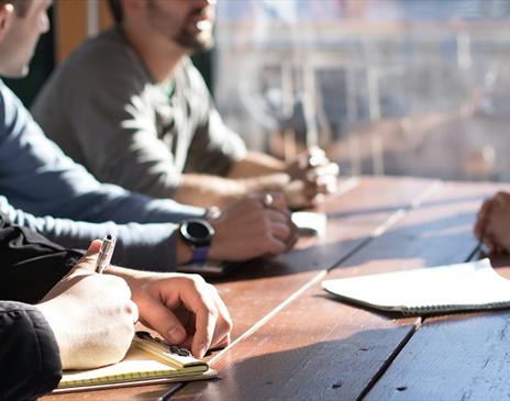 People sitting a table talking and taking notes