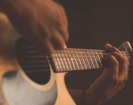 Person playing acoustic guitar with a capo